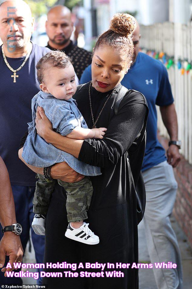 a woman holding a baby in her arms while walking down the street with